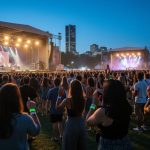 “Evening view of multiple illuminated music stages at LeBreton Flats during Ottawa Bluesfest with a diverse crowd in the foreground.”